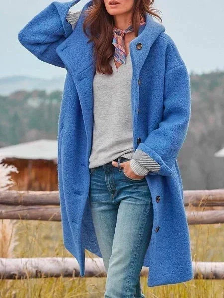Woman wearing long hooded coat with button front