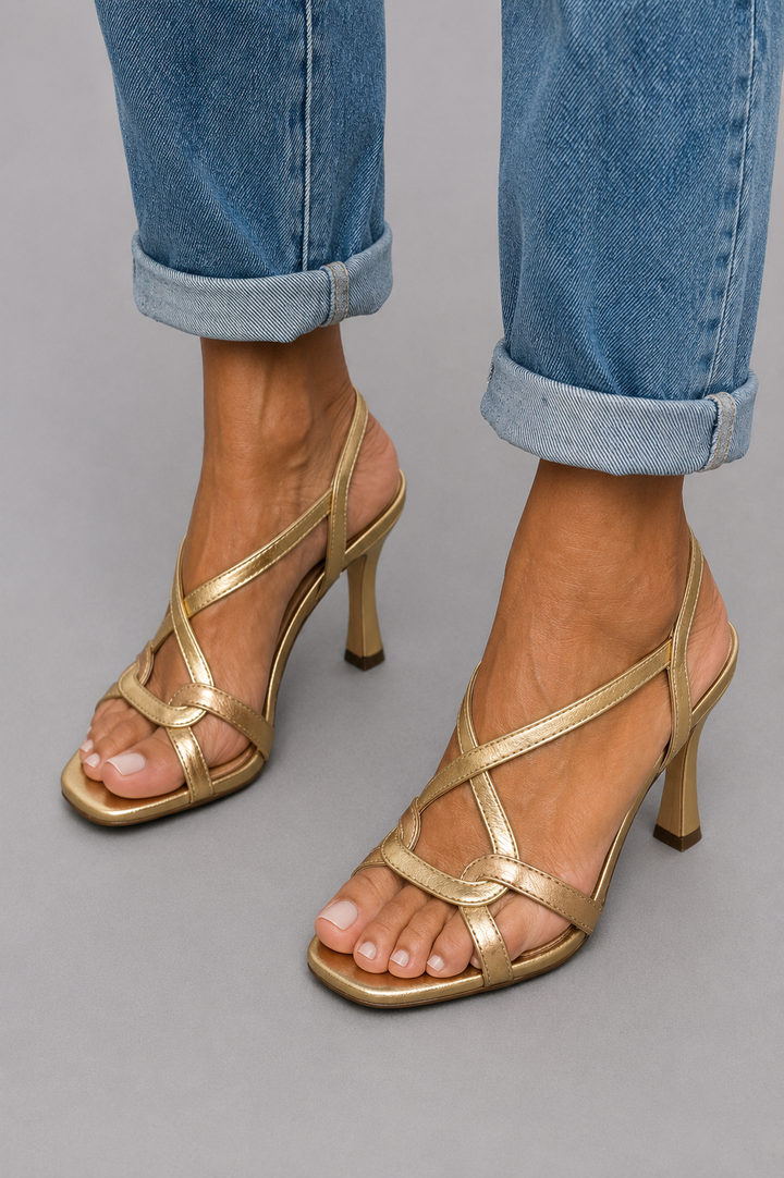 Woman wearing gold crossover strap heeled sandals